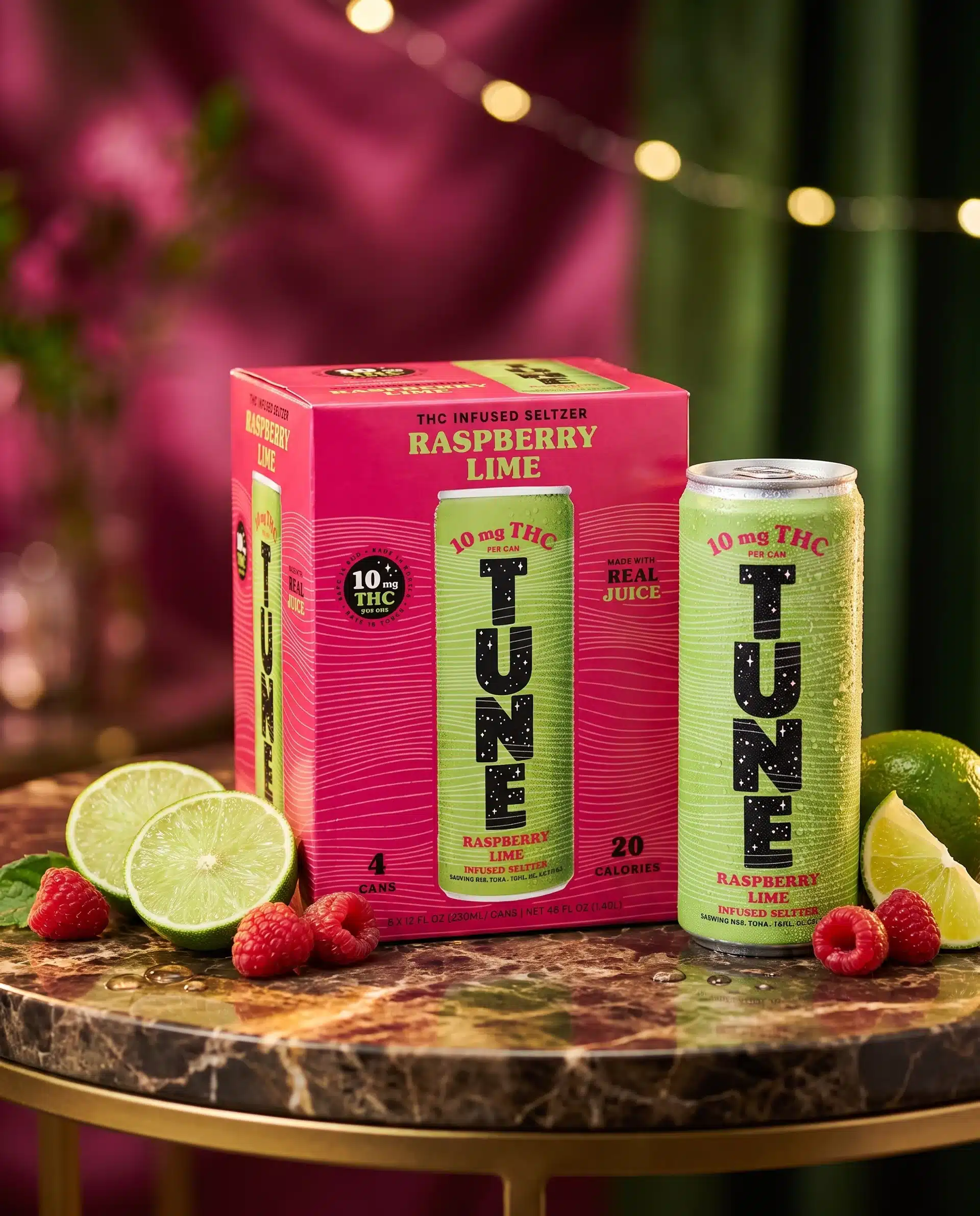A can and a four-pack of Tune Raspberry Lime THC seltzer on a marble table with raspberries and lime, set against a green and pink background with string lights.